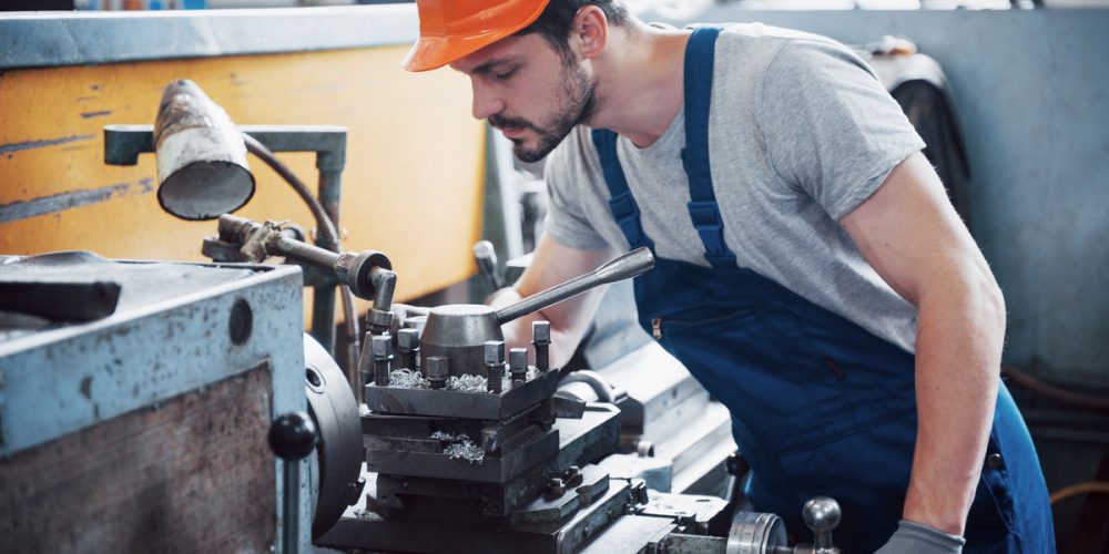 Portrait of a young worker in a hard hat at a large waste recycling factory. The engineer monitors the work of machines and other equipment.