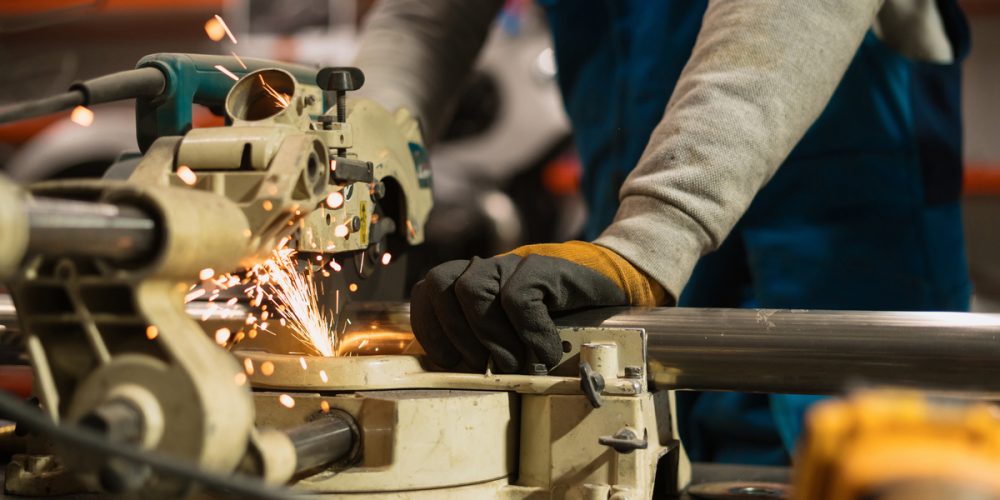 Technician worker cutting metal with many sharp sparks. Using equipments to cat iron